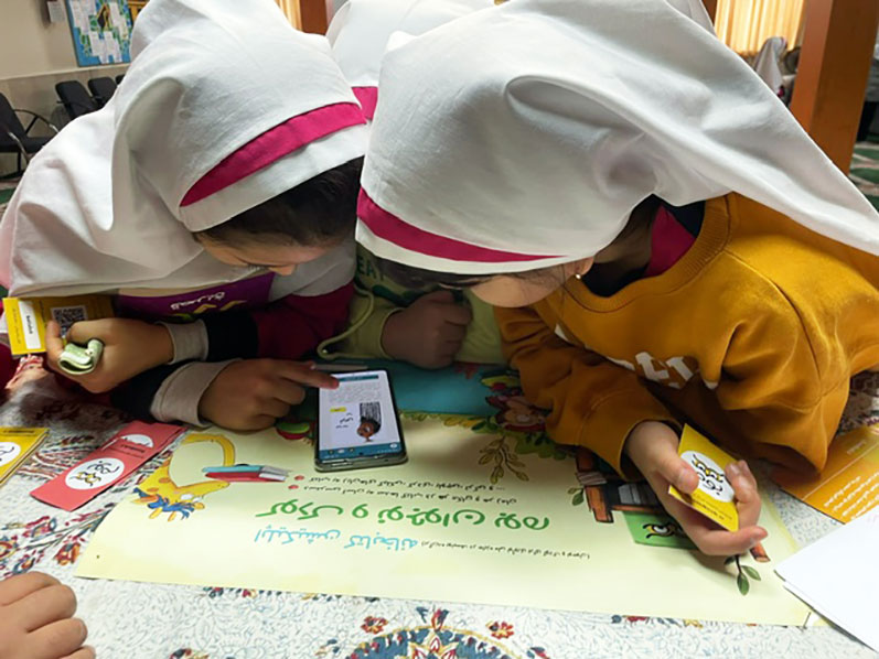 Two little girls reading a book on the Boom library application