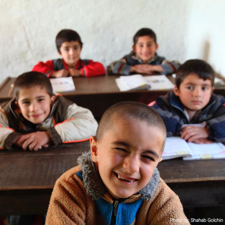Young students in a classroom smiling at the camera