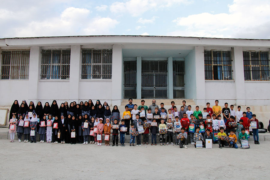 A wide shot of all the students and teachers standing in front or the school